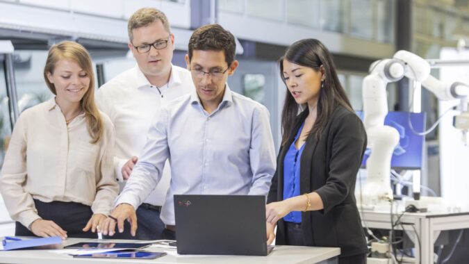 Gruppe von Personen steht um einen Laptop und bespricht sich