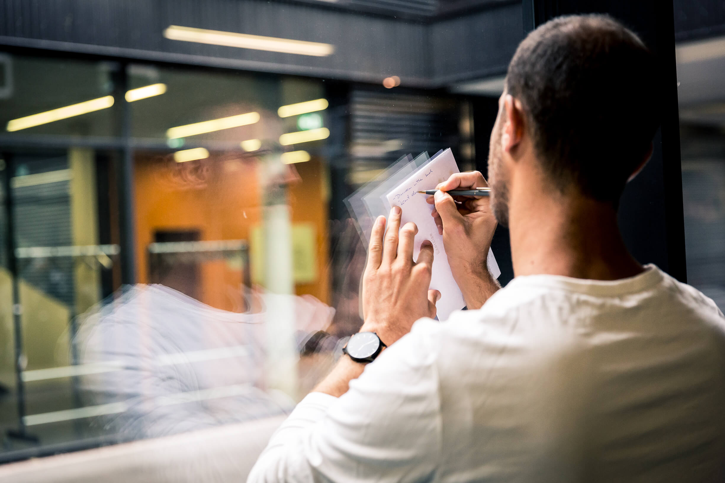 A man uses a window as a writing surface