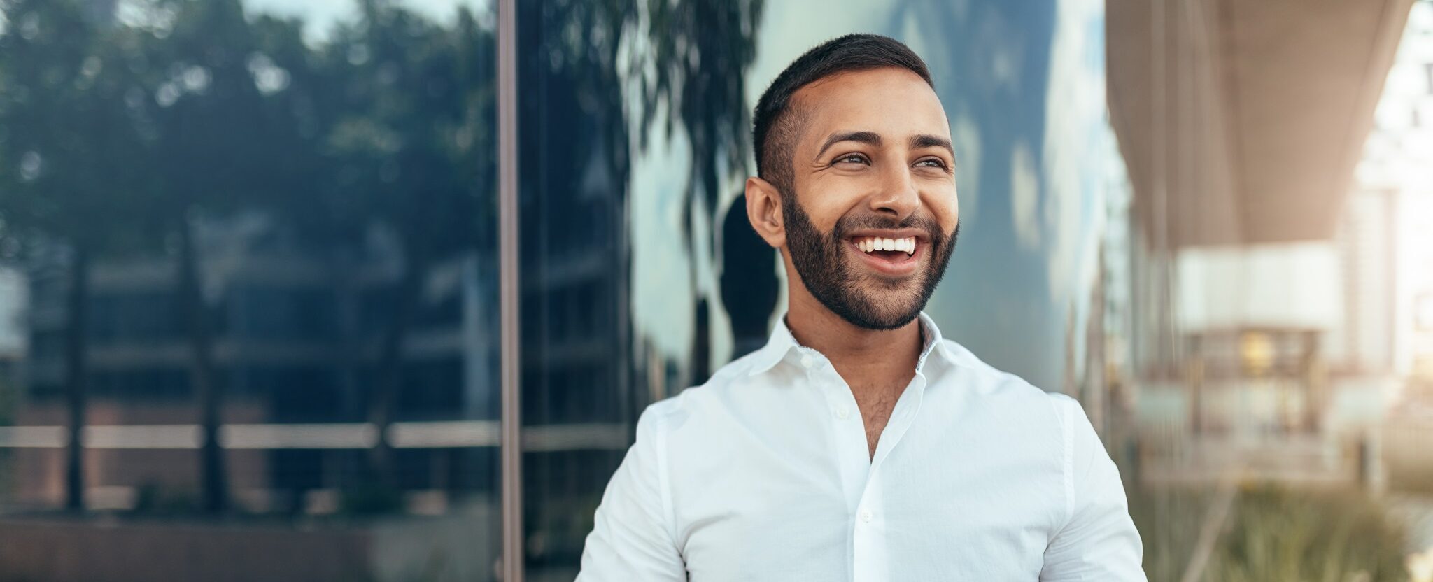 Portrait Of A Young Confident Smiling Indian Man Holding A Tablet And Looking Into The Distance