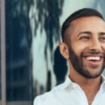 Portrait Of A Young Confident Smiling Indian Man Holding A Tablet And Looking Into The Distance