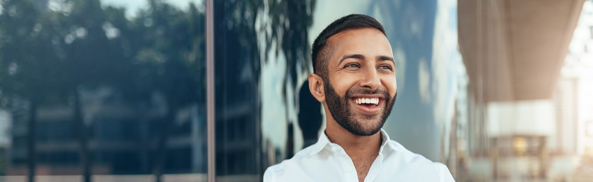 Portrait Of A Young Confident Smiling Indian Man Holding A Tablet And Looking Into The Distance